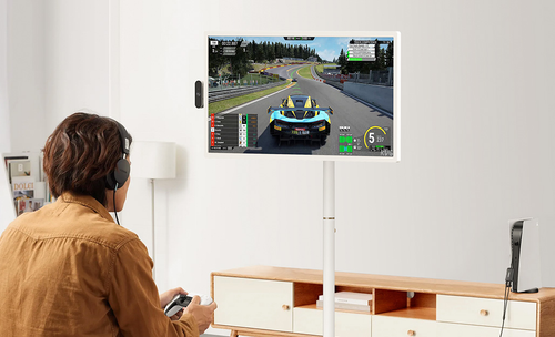 Man playing racing game on a wall-mounted TV with headset and controller